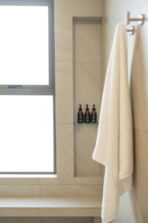 Ein Badezimmer mit Fenster, Ablage für Pflegeprodukte und Handtuchhalter.
