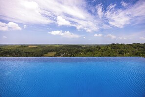 Ein klarer, blauer Himmel mit vereinzelten Wolken über einem Schwimmbecken.
