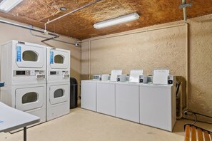 A laundry facility with stacked washers and dryers, a table, and a bench. - Beachfront Condo|Private Pool, Oceanfront Balcony (North Myrtle Beach)