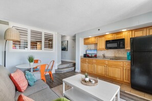 A modern living room with a sofa, a coffee table, and a dining area with chairs and a table. - Beachfront Condo|Private Pool, Oceanfront Balcony (North Myrtle Beach)