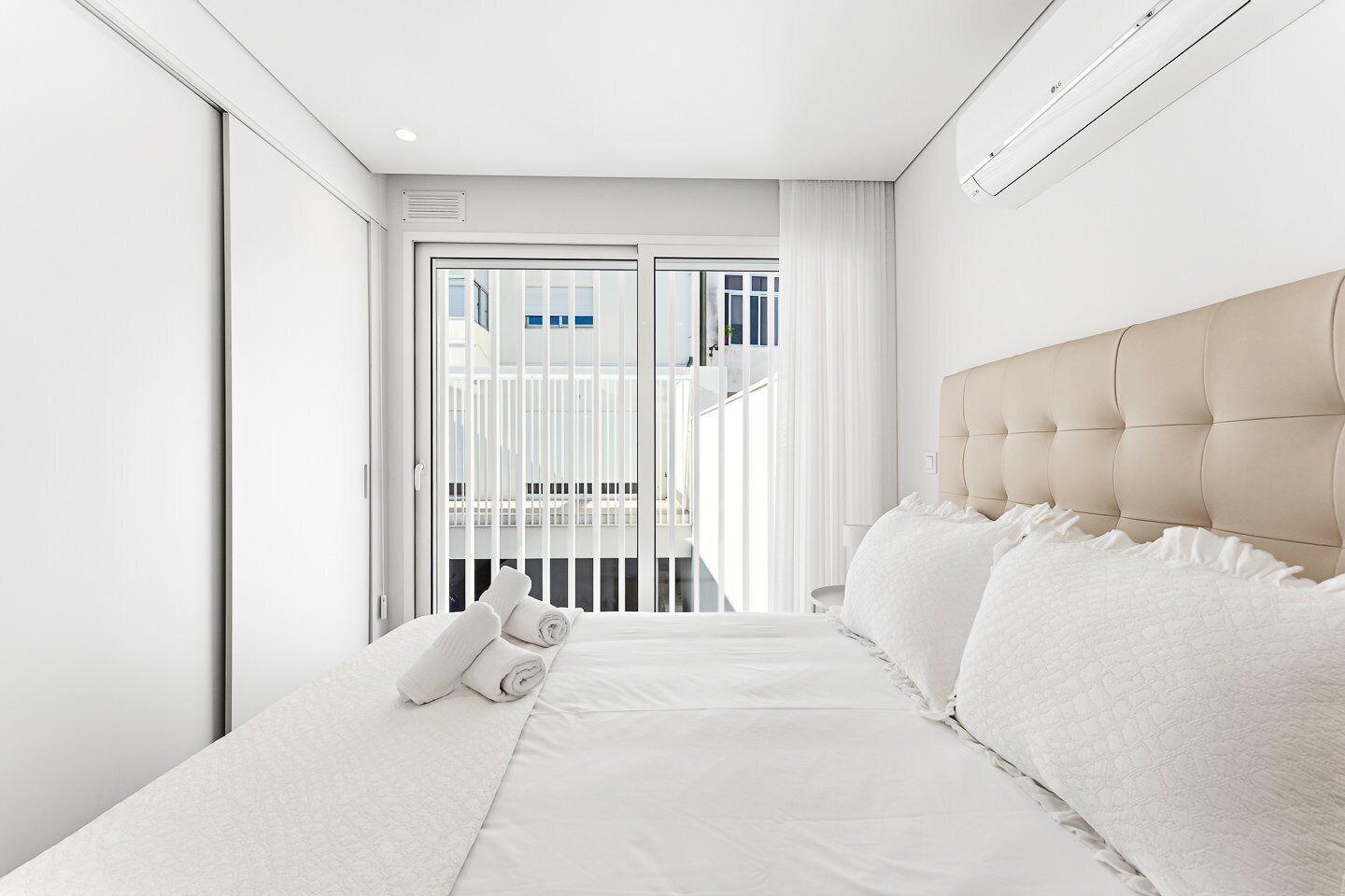 A hotel room with a bed, a balcony, and a view of the outside.
