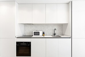 A compact kitchen with white cabinets, a microwave, a sink, and a dishwasher. - GuestReady-Modern Retreat with Private Balcony (Guimarães)