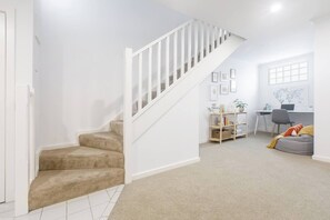 Eine Treppe führt zu einem Wohnbereich mit Schreibtisch, Bücherregal und Sitzsack.
