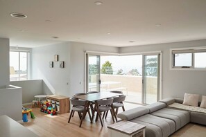 Ein modernes Wohnzimmer mit Essbereich, einer Couch und einem Kinderspielbereich.