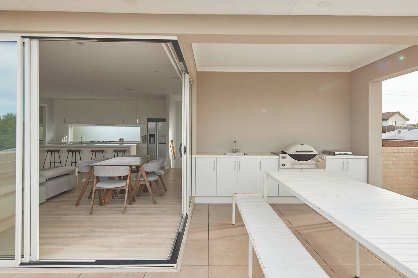 Una cocina moderna con comedor, puertas corredizas de vidrio que dan a un balcón y una parrilla.