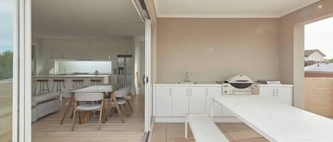 Una cocina moderna con comedor, puertas corredizas de vidrio que dan a un balcón y una parrilla.