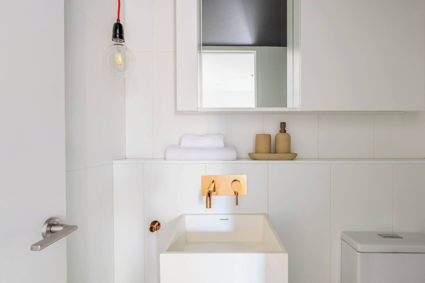 A modern bathroom with a white sink, a towel rack, and a mirror above the sink.