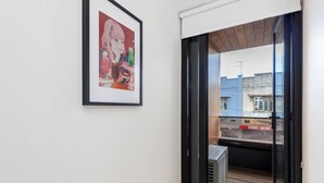 Um corredor com um quadro na parede, uma porta de vidro deslizante que dá para uma área externa e uma placa com a inscrição 'KEBABS GALORE' visível do lado de fora.