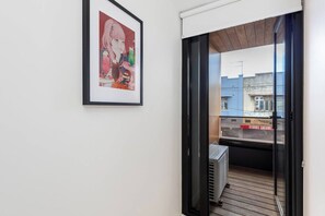 A hallway with a framed picture on the wall, a sliding glass door leading to an outdoor area, and a sign with 'KEBABS GALORE' visible outside. - Fitzroyals Uchi in Melbournes Multicultural Hub (Fitzroy)