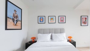 Quarto com uma cama, duas mesas de cabeceira e quatro quadros na parede.