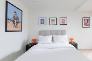 A bedroom with a bed, two nightstands, and four framed pictures on the wall. - Fitzroyals Uchi in Melbournes Multicultural Hub (Fitzroy)