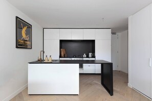 A modern kitchen with white cabinetry, a black countertop, and a herringbone wood floor. - Fitzroyals Uchi in Melbournes Multicultural Hub (Fitzroy)