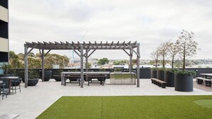 An outdoor patio area with a pergola, seating, planters, and a view of the cityscape. - Urban Drift Cosy Balcony Nook near Waterfront (Geelong)