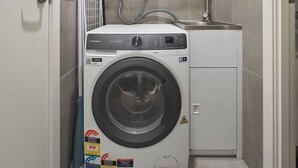 A compact laundry room with a front-loading washing machine, a sink, and a cabinet above. - Urban Drift Cosy Balcony Nook near Waterfront (Geelong)
