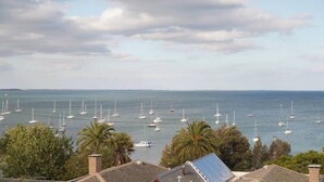 A marina with multiple sailboats docked, surrounded by palm trees and residential buildings. - Urban Drift Cosy Balcony Nook near Waterfront (Geelong)