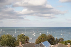 A marina with multiple sailboats docked, surrounded by palm trees and residential buildings. - Urban Drift Cosy Balcony Nook near Waterfront (Geelong)