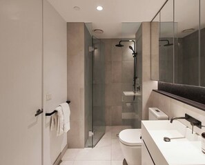 Une salle de bain moderne avec une douche à parois de verre, des toilettes blanches et un meuble-lavabo avec un miroir.