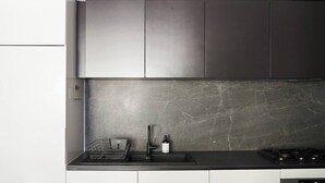 A modern kitchen with a marble backsplash, stainless steel appliances, and a minimalist design. - Modern Minimalism Slate Chic in the City (North Melbourne)