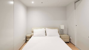 A minimalist hotel room with a large bed, a bedside table with a lamp, and a wardrobe. - Urban Artistry Loft A Haven Above the Bustle (Melbourne)