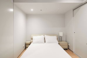 A minimalist hotel room with a large bed, a bedside table with a lamp, and a wardrobe. - Urban Artistry Loft A Haven Above the Bustle (Melbourne)
