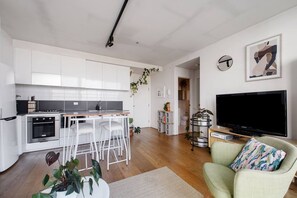 A modern apartment with a kitchen, dining area, and living room. It includes a TV, a sofa, and a coffee table. - Eden of Abbotsford A Serene Escape off Johnston St (Abbotsford)