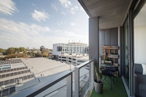 Een balkon met uitzicht op een stadsbeeld, een tafel met stoelen en een potplant.