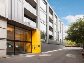 Een modern gebouw met een glazen entree en een geel accentmuur.