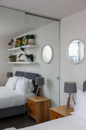 A modern bedroom with a bed, bedside tables, a mirror, and shelves with plants. - Eden of Abbotsford A Serene Escape off Johnston St (Abbotsford)