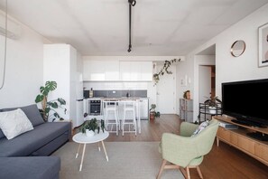 A modern living room with a grey sofa, a green armchair, a coffee table, and a TV on a wooden stand. - Eden of Abbotsford A Serene Escape off Johnston St (Abbotsford)