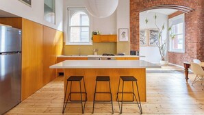 Una cocina moderna con una isla grande, armarios de madera y una pared decorada con ladrillos.