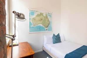 A room with a bed, a map on the wall, a desk, and a lamp. - Foy and Gibson An Industrial Chic Historic Warehouse (Collingwood)