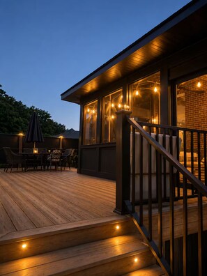 A wooden deck with outdoor furniture and a staircase leading to a covered area with windows. - Spacious Family Retreat Near Ann Arbor & U-M (Ypsilanti)