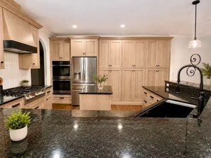 Eine moderne Küche mit Granit Arbeitsplatten, Edelstahlgeräten und Holzschränken.
