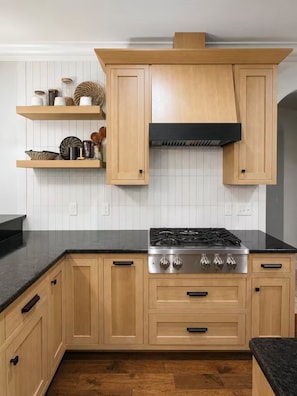A kitchen with wooden cabinets, a black countertop, and a stainless steel stove. - Spacious Family Retreat Near Ann Arbor & U-M (Ypsilanti)
