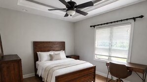 A bedroom with a wooden bed, a desk, and a ceiling fan. - Spacious Family Retreat Near Ann Arbor & U-M (Ypsilanti)