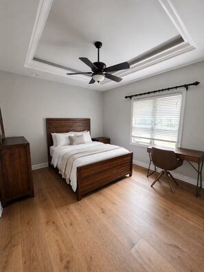 Ein Schlafzimmer mit einem hölzernen Bett, einem Schreibtisch und einem Deckenventilator.