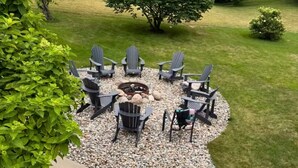 A patio with Adirondack chairs, a fire pit, and a gravel area. - Spacious Family Retreat Near Ann Arbor & U-M (Ypsilanti)