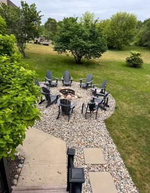 Eine Terrasse mit Adirondack-Stühlen, einer Feuerstelle und einem Kiesbereich.