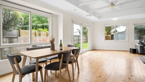Um quarto amplo com uma mesa de jantar de madeira, cadeiras e um ventilador de teto.