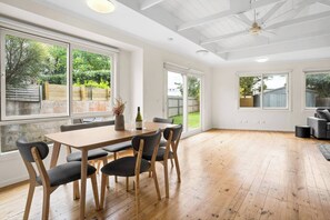 A spacious room with a wooden dining table, chairs, and a ceiling fan. - Cabinesque Comfort A Refreshing Beachside Retreat (Barwon Heads)