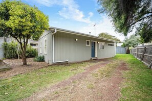 A single-story building with a front door, a small porch, and a fenced backyard. - Cabinesque Comfort A Refreshing Beachside Retreat (Barwon Heads)