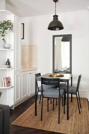 A dining area with a table, chairs, a rug, a hanging light fixture, and a mirror on the wall. - Nicholson Nook Parkside Stay near Dining and Culture (Fitzroy)