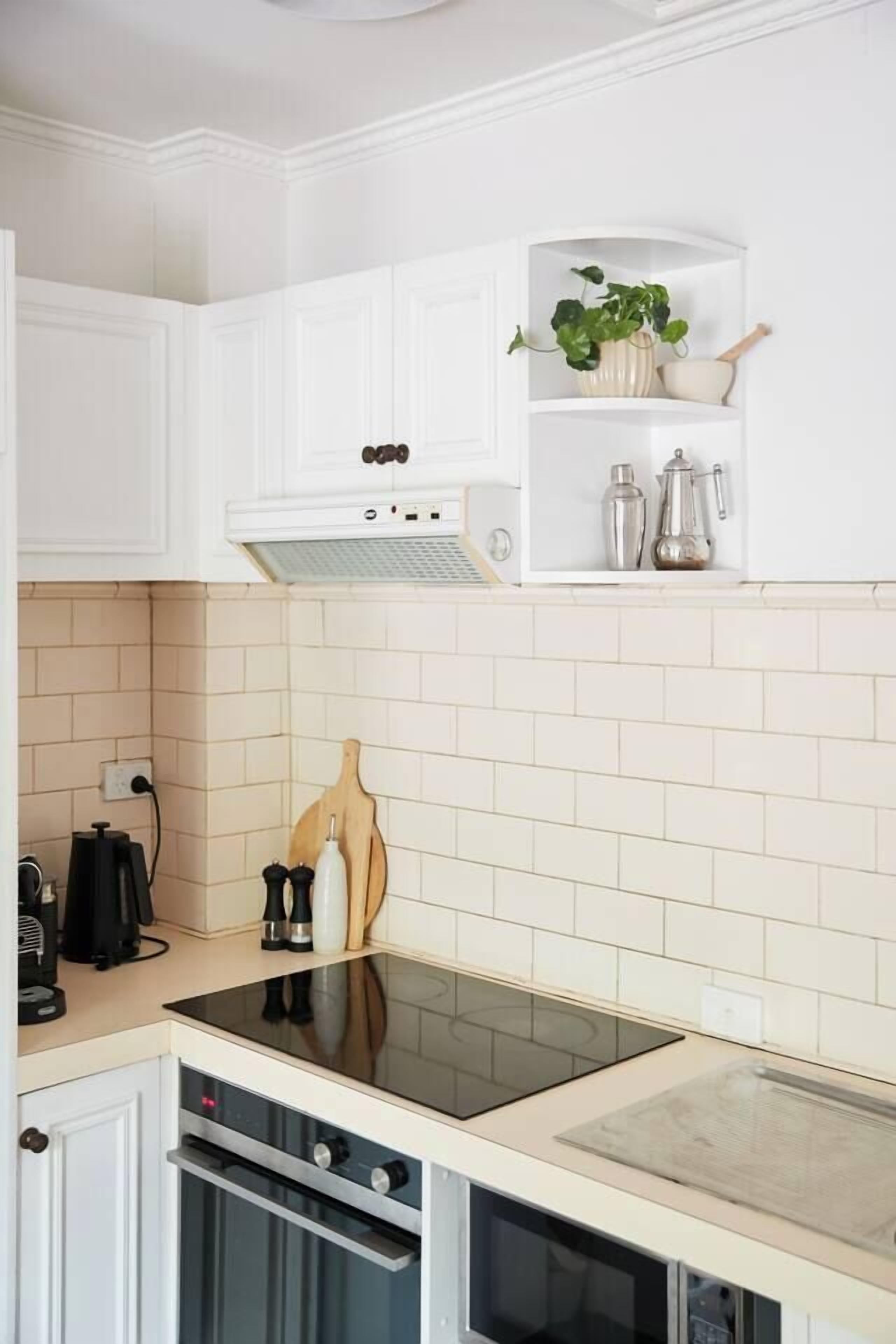 A kitchen with white cabinets, a black induction cooktop, and a built-in oven.
