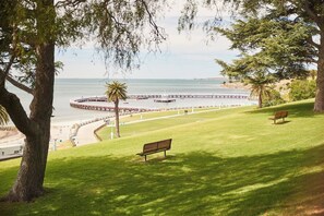 A grassy area with benches and a view of the sea. - Swanston Sands Sophisticated Comfort by the Beach (Geelong)