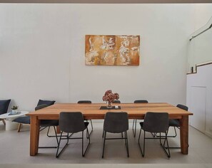 A conference room with a wooden table, six chairs, a vase with flowers, and a painting on the wall. - Swanston Sands Sophisticated Comfort by the Beach (Geelong)