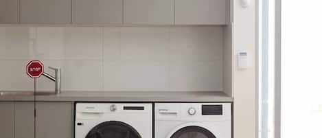 A laundry area with two washing machines, a stop sign, and a door leading to an outdoor area.