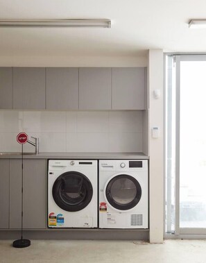 A laundry area with two washing machines, a stop sign, and a door leading to an outdoor area. - Swanston Sands Sophisticated Comfort by the Beach (Geelong)