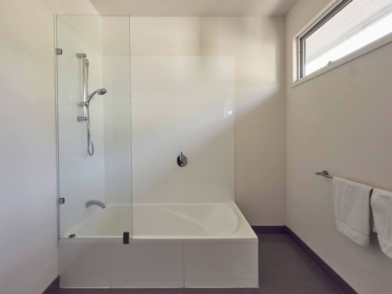 Ein modernes Badezimmer mit einer Duschkabine, einer freistehenden Badewanne und einem Handtuchhalter.