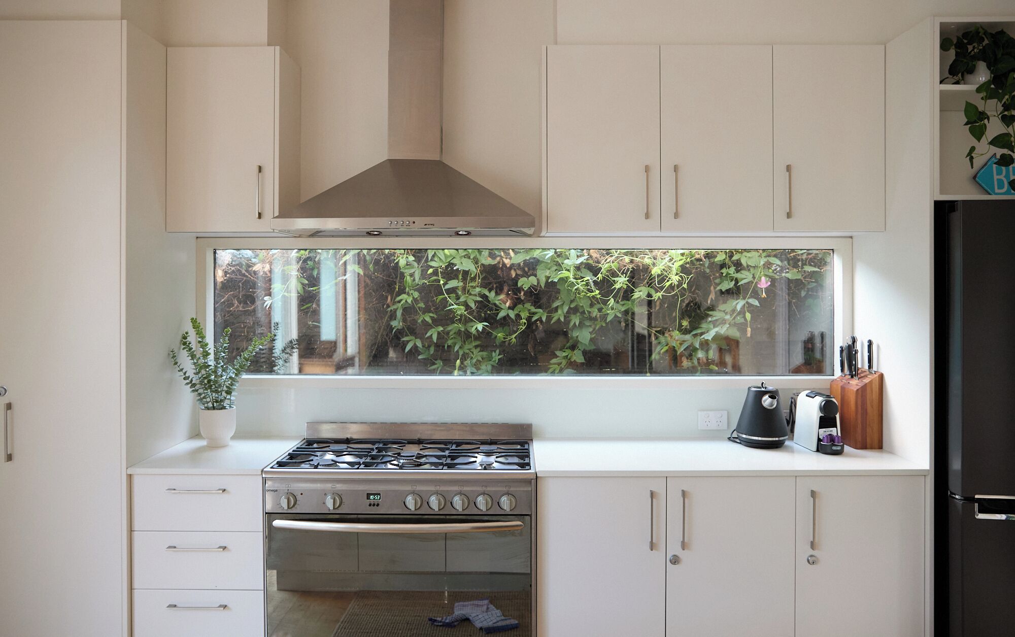 Una cucina con piano cottura a gas, forno e una grande finestra con vista sul verde.