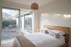 Ein Schlafzimmer mit einem großen Schiebeglasfenster, das auf eine Außenpatio führt.